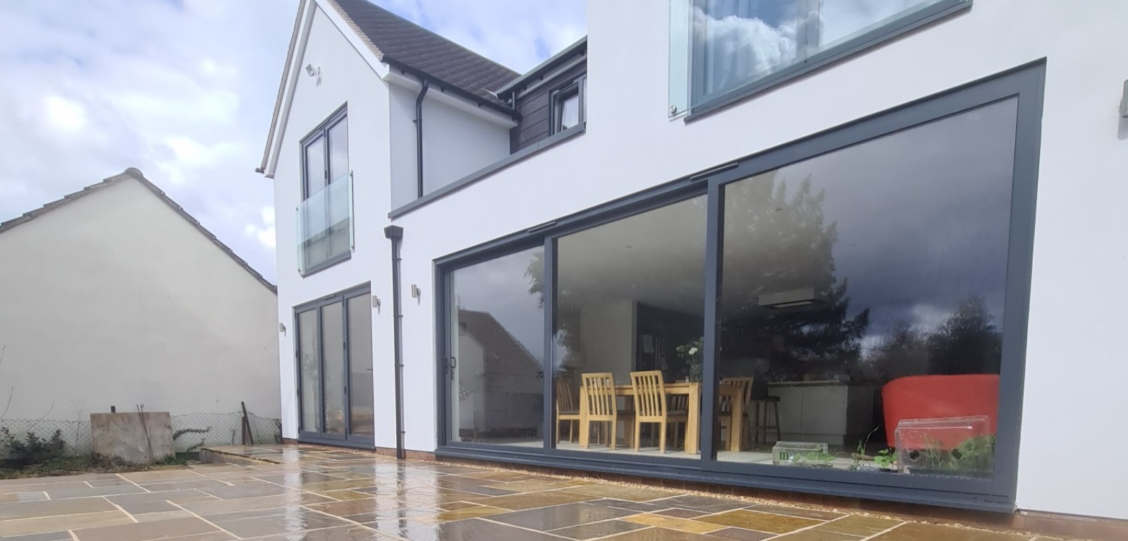 PROJECT extension, with a large double story rear and side build, white render and dark cladding,.