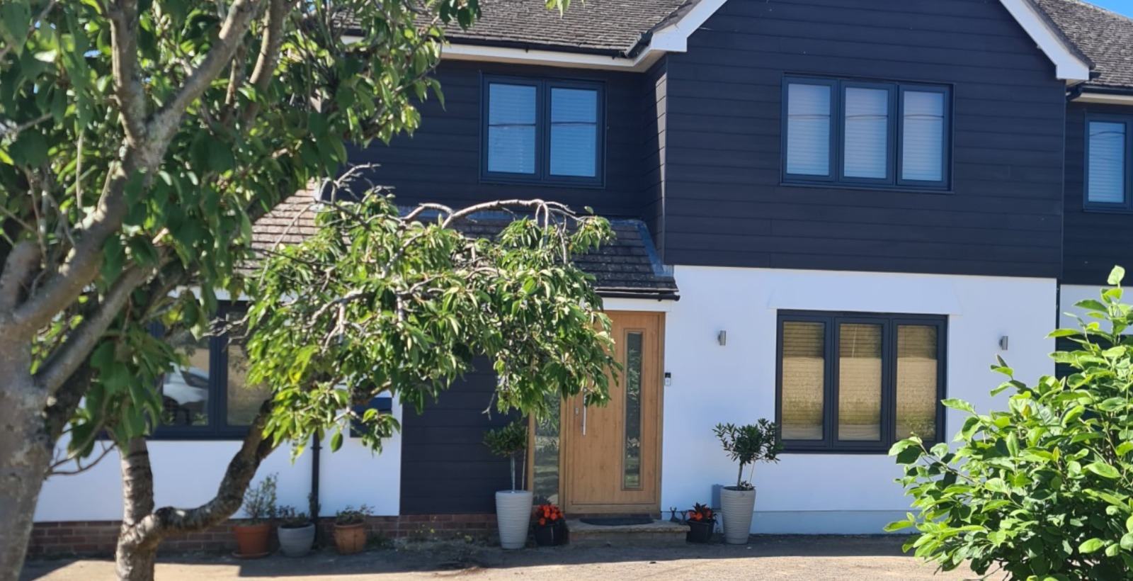 RADLEY PROJECT A stunning extension to this lovely property, with a large double story rear and side build, white render and dark cladding,.